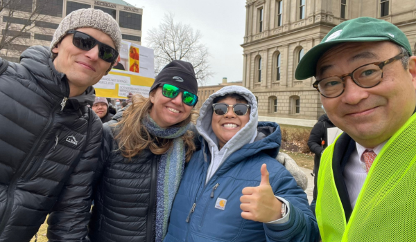 Four Stand Up for Science participants showing their support of the rally in front of the capital.